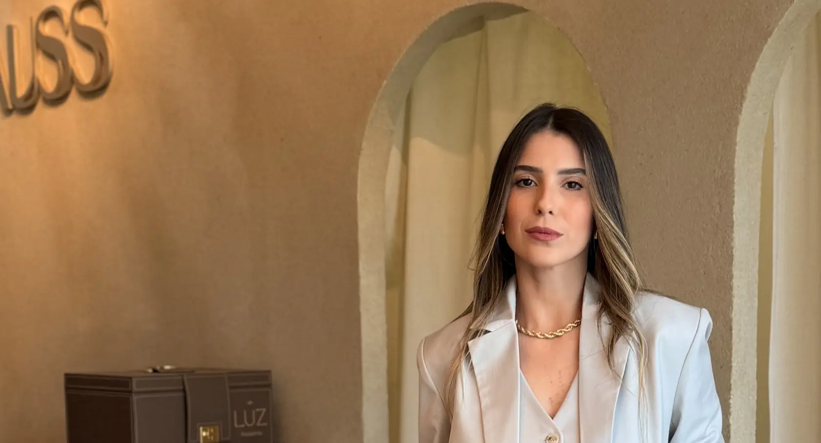 A Ana Laura na loja Lauss, com o letreiro metálico na parede e a cortina de linho